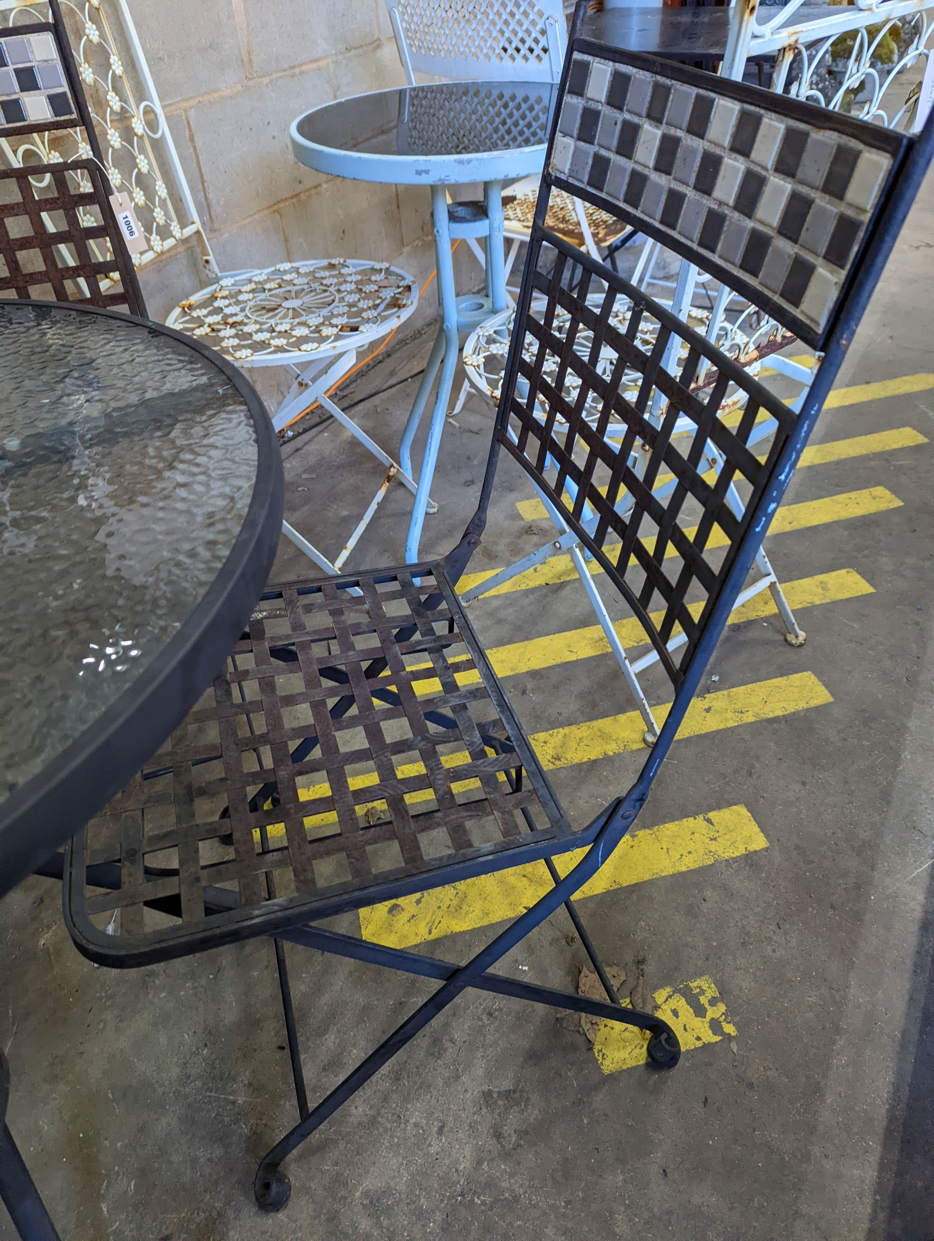 A circular glass top garden table, diameter 80cm, height 71cm and four metal folding garden chairs